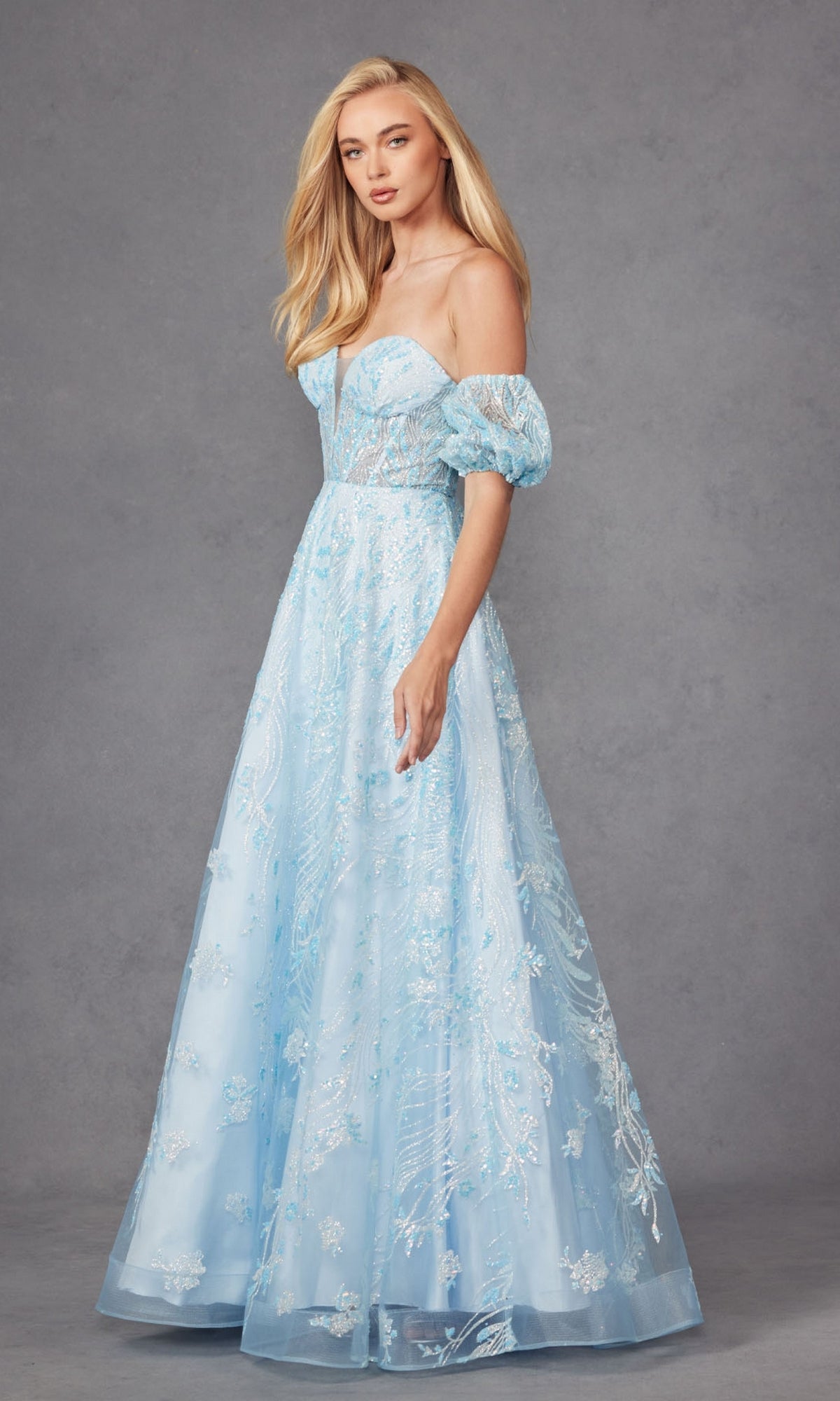 A woman models the Puff-Sleeve Strapless Long Glitter Prom Dress 2404 in light blue, featuring lace details, against a plain gray background.